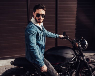 Klasik tarzı siyah motosiklet ile yakışıklı sakallı motorcu. Cafe racer.