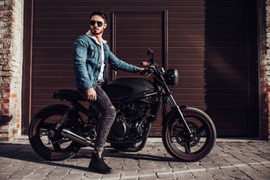 Klasik tarzı siyah motosiklet ile yakışıklı sakallı motorcu. Cafe racer.