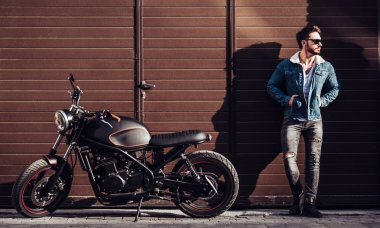 Klasik tarzı siyah motosiklet ile yakışıklı sakallı motorcu. Cafe racer.