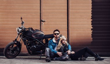 Romantik motorcu çift siyah motosiklet ile. Yakışıklı adam ve genç çekici kadın kafe racer ile açık havada sakallı.