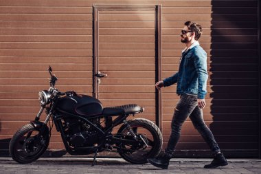 Klasik tarzı siyah motosiklet ile yakışıklı sakallı motorcu. Cafe racer.