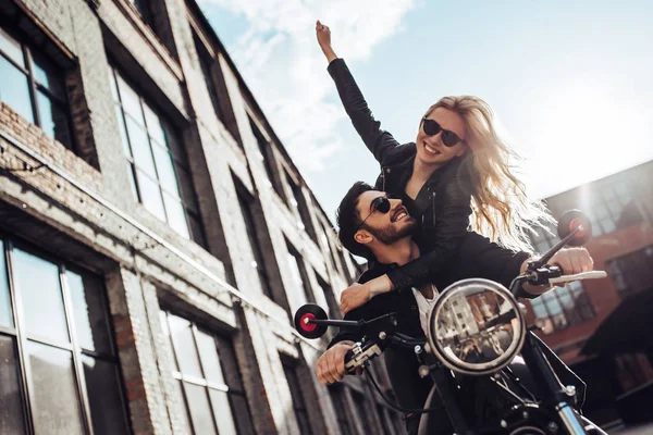 Romantic biker couple with black motorcycle. Handsome bearded man and young attractive woman outdoors with cafe racer.