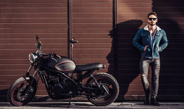 Klasik tarzı siyah motosiklet ile yakışıklı sakallı motorcu. Cafe racer.