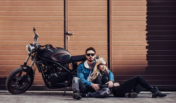 Romantik motorcu çift siyah motosiklet ile. Yakışıklı adam ve genç çekici kadın kafe racer ile açık havada sakallı.