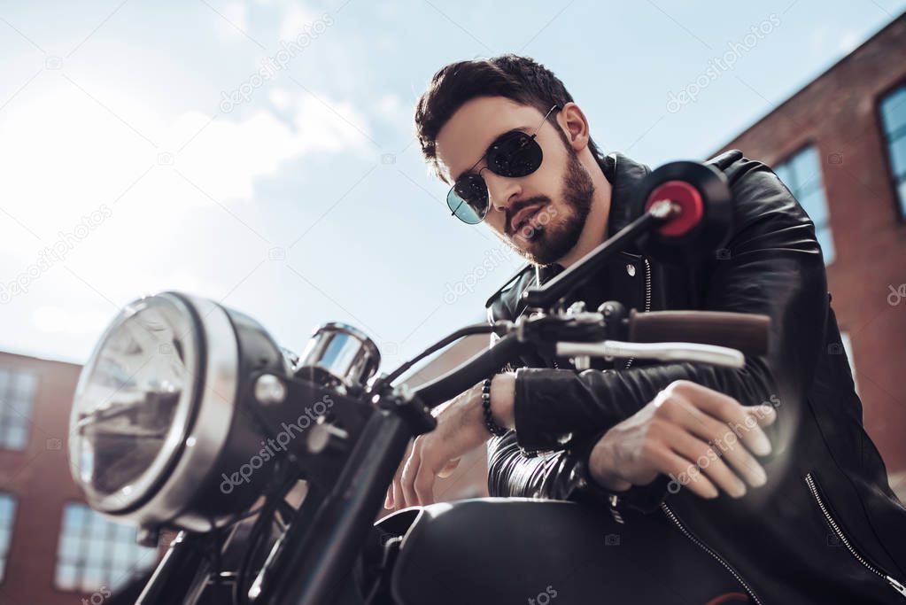 Handsome bearded biker with classic style black motorcycle. Cafe racer.
