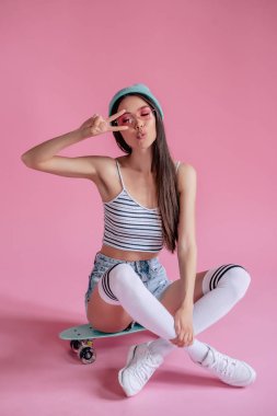 Pembe pembe gözlüklü Genç Asyalı Genç kızı. Patenci kız şort izole kaykay ile.