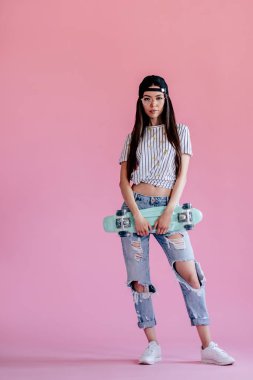 Genç Asyalı Genç kız pembe bir arka plan üzerinde. İzole kaykay ile şık genç kadın.