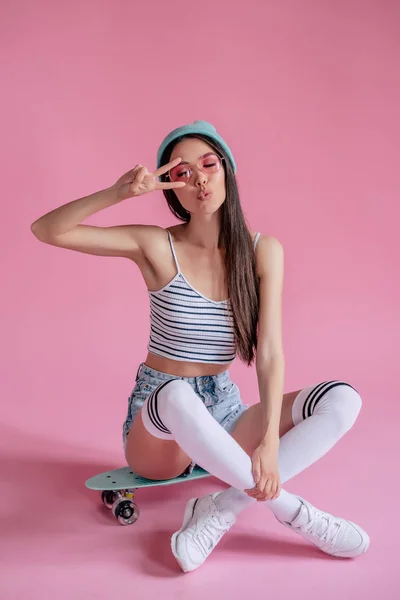 年轻的亚裔少女粉红色的背景粉红色的眼镜 滑板女孩在短裤与滑板隔离 — 图库照片