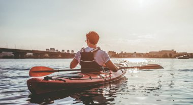 Sportif yakışıklı günbatımı üzerinde kayak. Yalnız Kano.