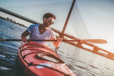 Sportif yakışıklı sunset bulvarında Nehri üzerinde kayak. Yalnız Kano.