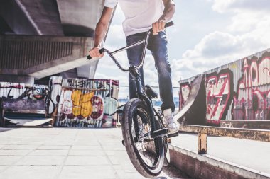 Genç Bmx sürücüsü kırpılmış görüntü hileler skatepark içinde gerçekleştiriyor.