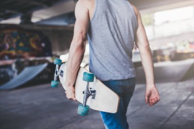 Genç adam kaykaycı kırpılmış görüntü. Erkek genç skatepark longboard ile.