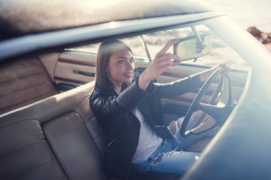 Çekici genç kadın sahilde yeşil retro arabada oturuyor. Vintage Klasik Otomobil.