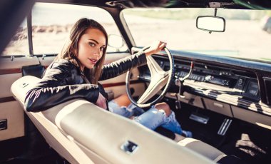 Çekici genç kadın sahilde yeşil retro arabada oturuyor. Vintage Klasik Otomobil.