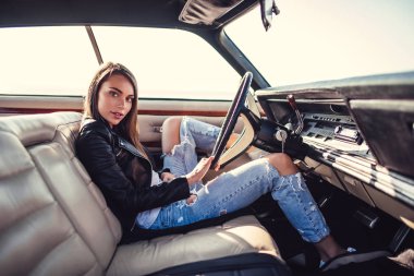 Çekici genç kadın sahilde yeşil retro arabada oturuyor. Vintage Klasik Otomobil.