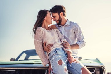 Romantik çift sahilde yeşil retro car yakınındaki duruyor. Sakallı yakışıklı ve çekici genç kadın eski model klasik araba. Aşk hikayesi.