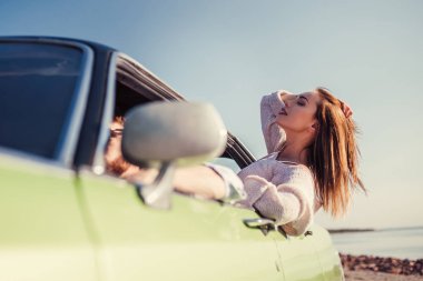 Macera ruhu hissediyorum! Adam araba kullanırken çekici genç kadın yeşil retro araba penceresinden meyilli. Vintage Klasik Otomobil.