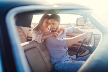 Romantik çift sahilde yeşil retro arabada oturuyor. Sakallı yakışıklı ve çekici genç kadın vintage klasik araba. Şık aşk hikayesi. Sarılma ve öpüşme arabaya olurken.