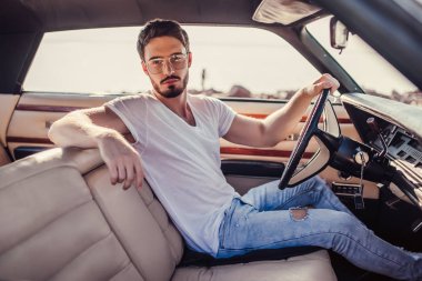 Yakışıklı sakallı adam onun yeşil retro araba ayakta sahilde oturuyor. Vintage Klasik Otomobil.