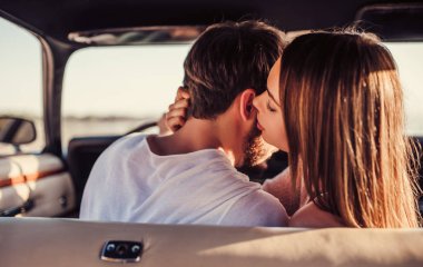 Romantik çift sahilde yeşil retro arabada oturuyor. Sakallı yakışıklı ve çekici genç kadın vintage klasik araba. Şık aşk hikayesi. Sarılma ve öpüşme arabaya olurken.