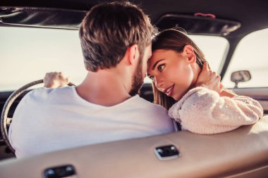 Romantik çift sahilde yeşil retro arabada oturuyor. Sakallı yakışıklı ve çekici genç kadın vintage klasik araba. Şık aşk hikayesi. Sarılma ve öpüşme arabaya olurken.