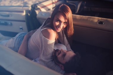 Romantik çift sahilde yeşil retro arabada oturuyor. Sakallı yakışıklı ve çekici genç kadın vintage klasik araba. Şık aşk hikayesi. Sarılma ve öpüşme arabaya olurken.