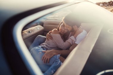 Romantik çift sahilde yeşil retro arabada oturuyor. Sakallı yakışıklı ve çekici genç kadın vintage klasik araba. Şık aşk hikayesi. Sarılma ve öpüşme arabaya olurken.