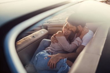 Romantik çift sahilde yeşil retro arabada oturuyor. Sakallı yakışıklı ve çekici genç kadın vintage klasik araba. Şık aşk hikayesi. Sarılma ve öpüşme arabaya olurken.