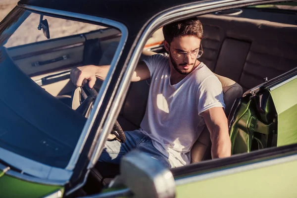 Yakışıklı sakallı adam onun yeşil retro araba ayakta sahilde oturuyor. Vintage Klasik Otomobil.