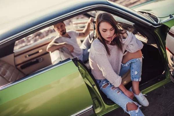 Romantik çift sahilde yeşil retro arabada oturuyor. Sakallı yakışıklı ve çekici genç kadın vintage klasik araba. Şık aşk hikayesi.