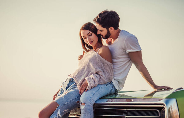 Романтическая пара стоит рядом с зеленым ретро автомобилем на пляже. Красивый бородатый мужчина и привлекательная молодая женщина с винтажной классической машиной. История любви
.
