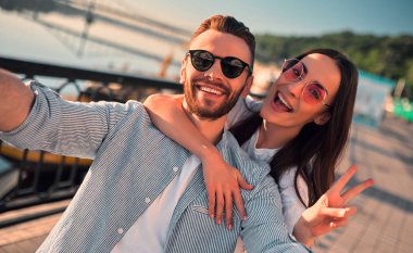 Havada aşk var! Şehirde birlikte vakit ve selfie yapma şirin romantik bir çift. Sakallı yakışıklı ve çekici genç kadın aşığız. Sarılma, Öpüşme ve gün batımı sırasında having fun.