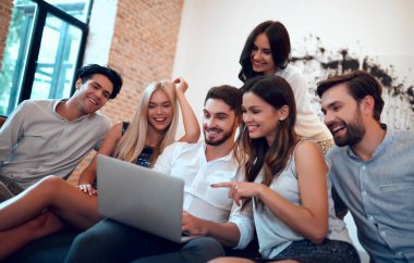 Hadi parti başlasın! Bir grup genç insan birlikte eğleniyor. Yakın arkadaş büyük şirket içinde laptop ile kanepede oturan.