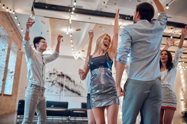 Hadi parti başlasın! Bir grup genç insan birlikte eğleniyor. Şampanya ve konfeti düşen ışık oda dans. Büyük şirket yakın arkadaşım tatil kutluyor.