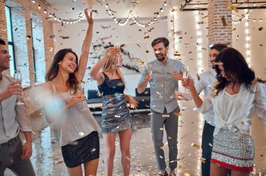 Hadi parti başlasın! Bir grup genç insan birlikte eğleniyor. Şampanya ve konfeti düşen ışık oda dans. Büyük şirket yakın arkadaşım tatil kutluyor.