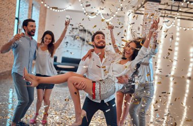 Hadi parti başlasın! Bir grup genç insan birlikte eğleniyor. Şampanya ve konfeti düşen ışık oda dans. Büyük şirket yakın arkadaşım tatil kutluyor.