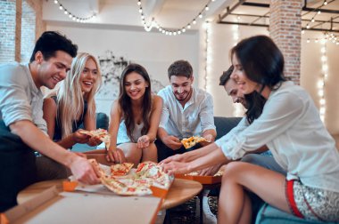 Hadi parti başlasın! Bir grup genç insan birlikte eğleniyor. Büyük ışık odada şampanya ve pizza ile oturuyor. Büyük şirket yakın arkadaşım tatil kutluyor.