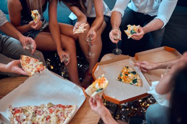 Hadi parti başlasın! Grup Genç insan birlikte eğleniyor resim kırpılmış. Büyük ışık odada şampanya ve pizza ile oturuyor. Büyük şirket yakın arkadaşım tatil kutluyor.
