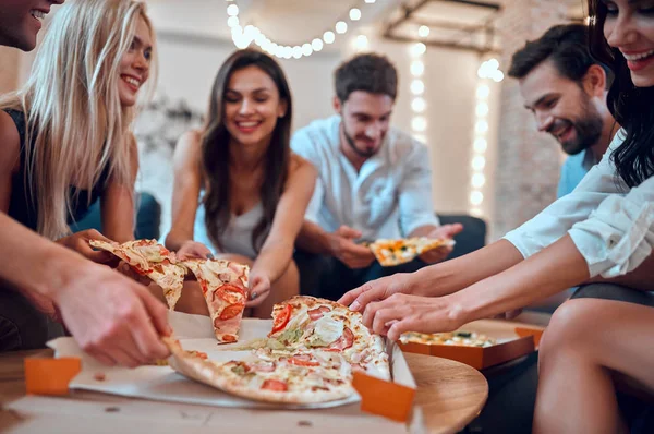 Hadi parti başlasın! Bir grup genç insan birlikte eğleniyor. Büyük ışık odada şampanya ve pizza ile oturuyor. Büyük şirket yakın arkadaşım tatil kutluyor.