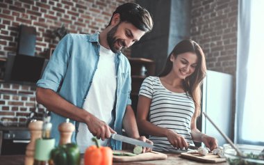 Romantik Çift mutfak yemek pişiriyor. Yakışıklı ve çekici genç kadın birlikte salata yaparken eğleniyor musun. Sağlıklı yaşam konsepti.