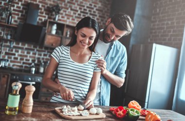 Romantik Çift mutfak yemek pişiriyor. Yakışıklı ve çekici genç kadın birlikte salata yaparken eğleniyor musun. Sağlıklı yaşam konsepti.