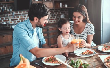 Anne, baba ve kızı mutfak birlikte yemek yiyor. Mutlu aile kavramı.