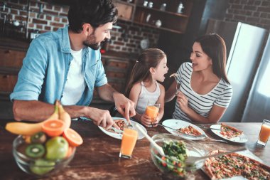 Anne, baba ve kızı mutfak birlikte yemek yiyor. Mutlu aile kavramı.