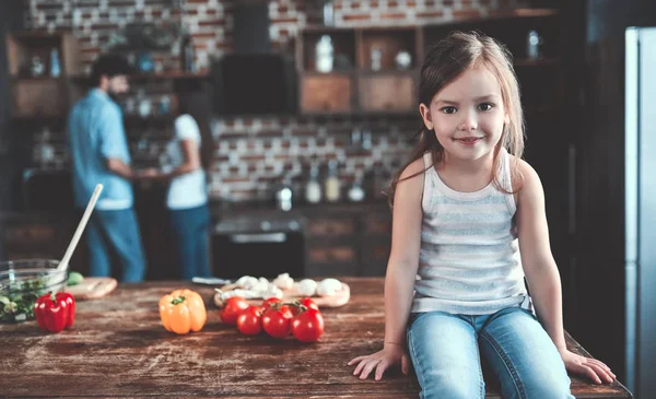 Mom, dad and daughter are cooking on kitchen. Happy family concept. Handsome man, attractive young woman and their cute little daughter are making salad together. Healthy lifestyle.