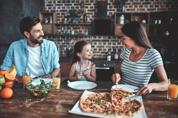 Mom, dad and daughter are eating together on kitchen. Happy family concept.