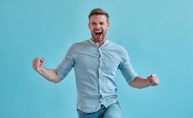 Yakışıklı adam izole heyecanlı. Mavi arka plan üzerinde poz şık genç adam.