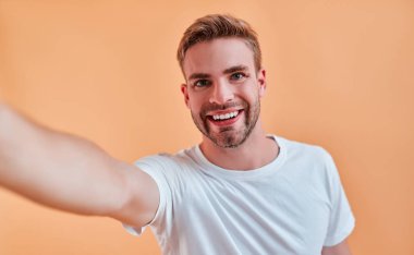Yakışıklı adam izole. Poz ve yapım selfie turuncu zemin üzerine şık genç adam.