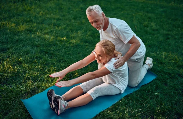 Senior couple is doing sport outdoors. Stretching in park during sunrise. Doing yoga together. Healthy lifestyle concept