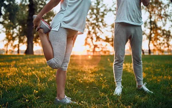 年配のカップルは屋外のスポーツをやっています 日の出中に公園でストレッチ — ストック写真