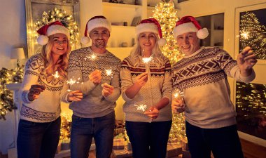 Mutlu Noeller ve mutlu yeni yıl! Mutlu aile kutluyor kış tatili evde. Anne ve büyükanne ve büyükbaba Noel yılbaşı ağacı elinde havai fişekleri ile yakın dururken bekliyor.